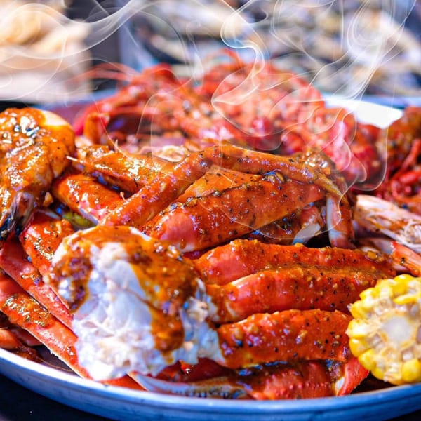 Steaming crab legs and shrimp covered in sauce, with corn on the cob, from The Crab Station.
